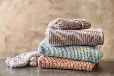 Photo of Stack of warm knitted clothes on table