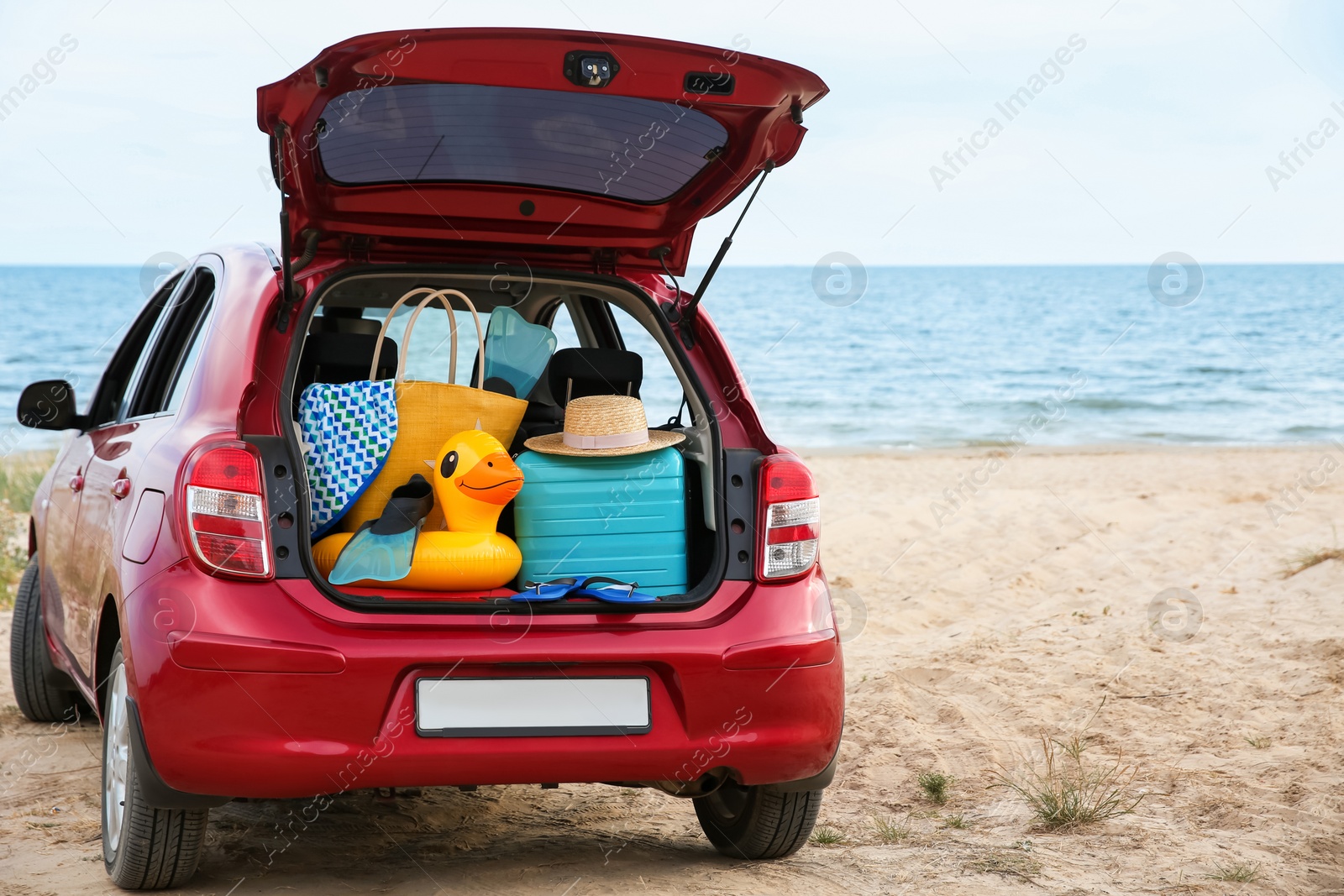 Photo of Red car with luggage on beach. Summer vacation trip