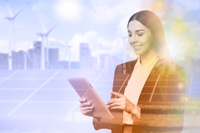 Multiple exposure of businesswoman with tablet, wind turbines and solar panels installed outdoors. Alternative energy source