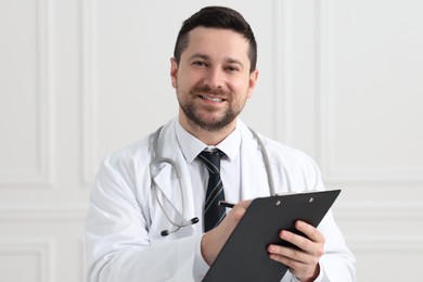 Photo of Smiling doctor with pen and clipboard indoors