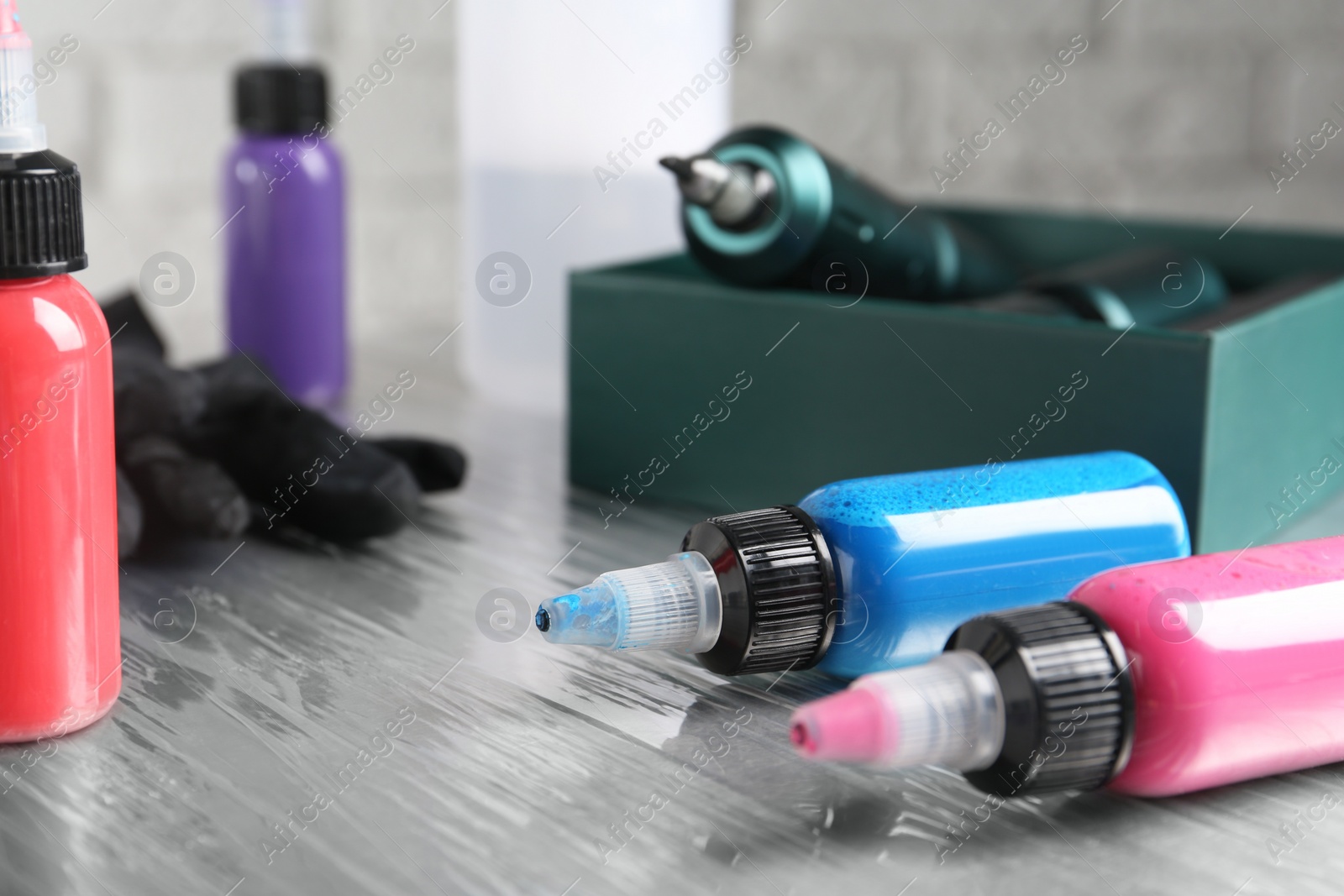 Photo of Bottles of colorful tattoo inks on table in salon