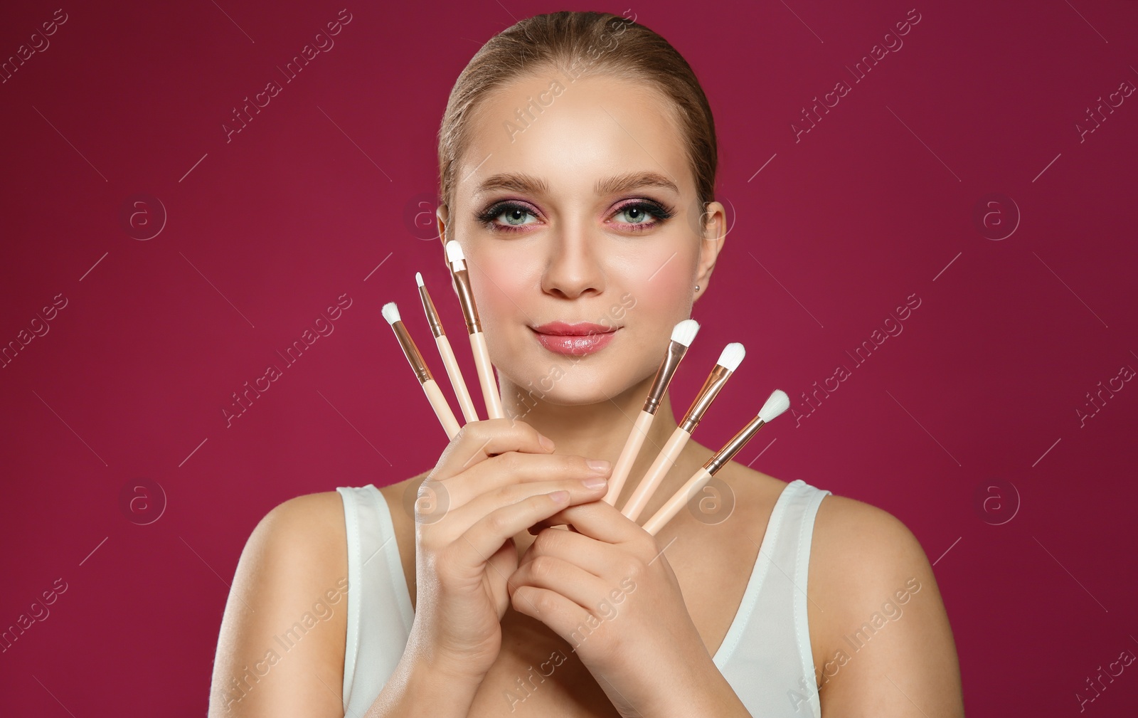 Photo of Beautiful woman with makeup brushes on pink background