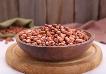 Photo of Bowl with dry kidney beans on white table, closeup
