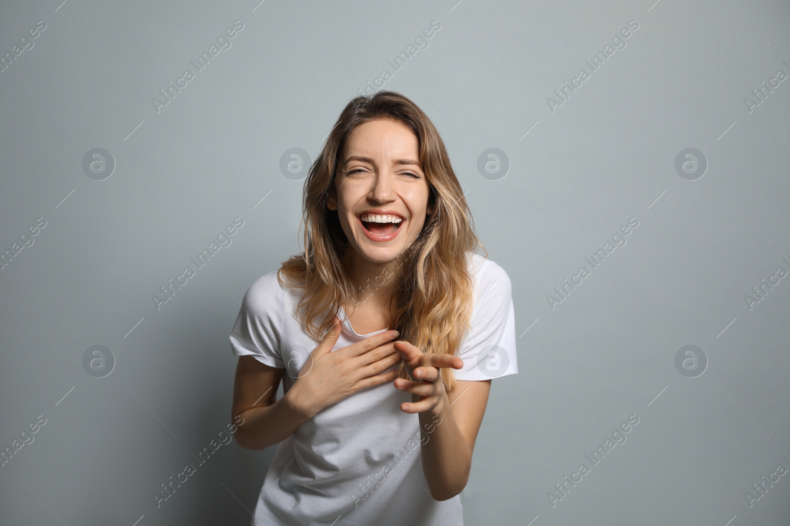 Photo of Cheerful young woman laughing on grey background