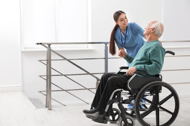 Photo of Nurse assisting senior man in wheelchair at hospital