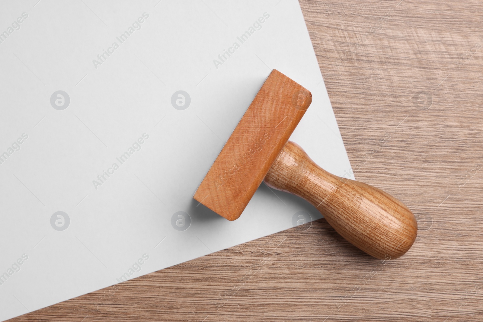 Photo of One stamp tool and sheet of paper on wooden table, top view. Space for text