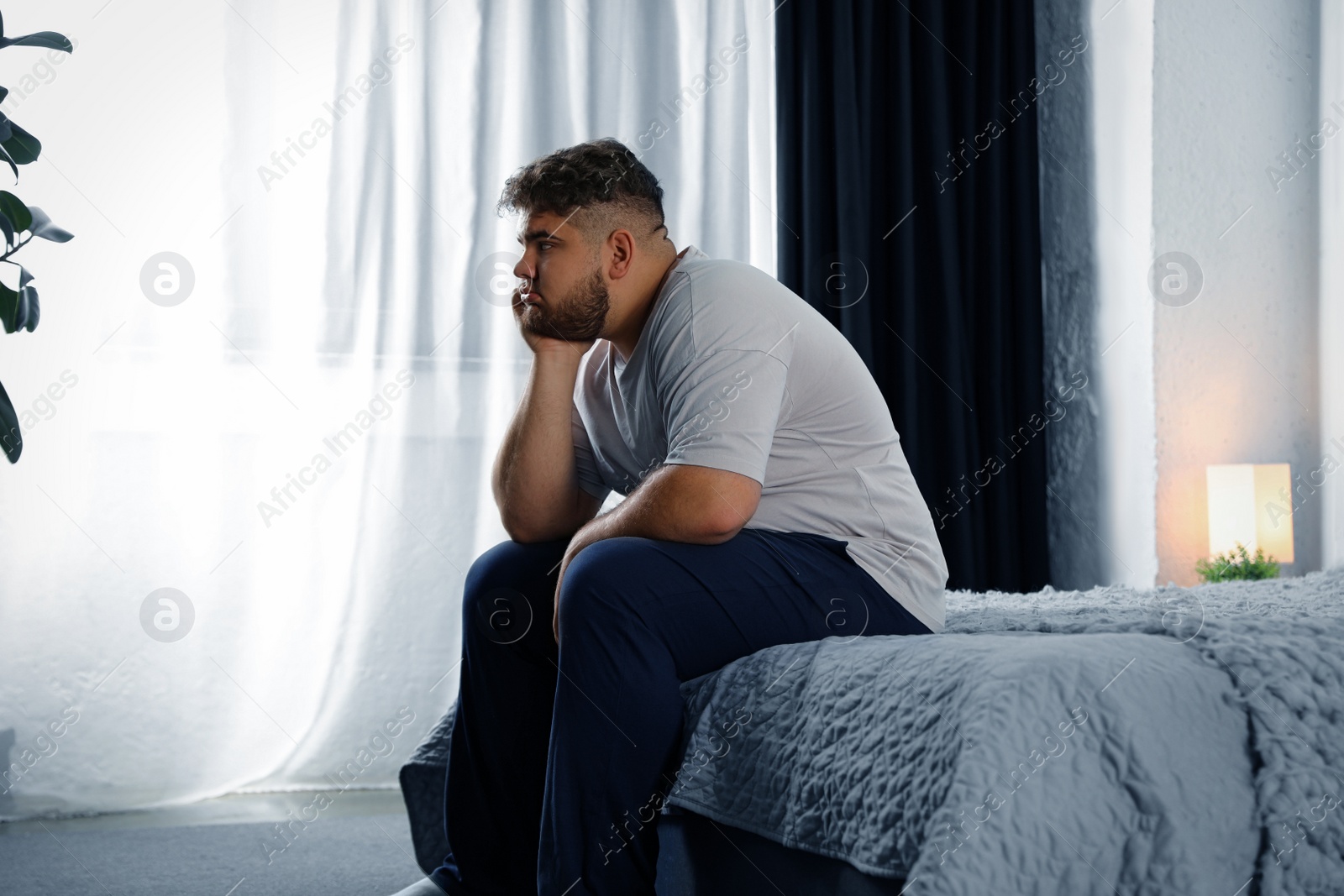 Photo of Depressed overweight man on bed at home