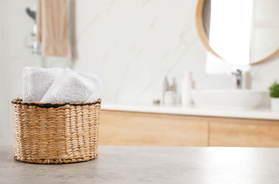 Photo of Rolled fresh towels on grey table in bathroom. Space for text