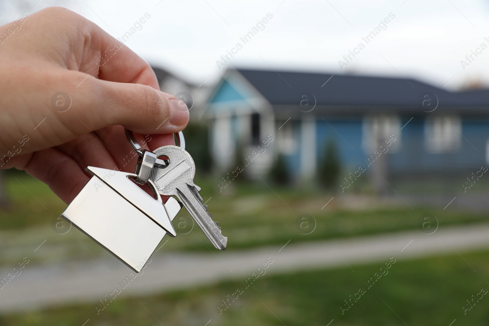 Photo of Woman holding house keys outdoors, closeup with space for text. Real estate agent