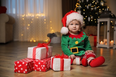 Baby in cute Christmas outfit with gifts at home