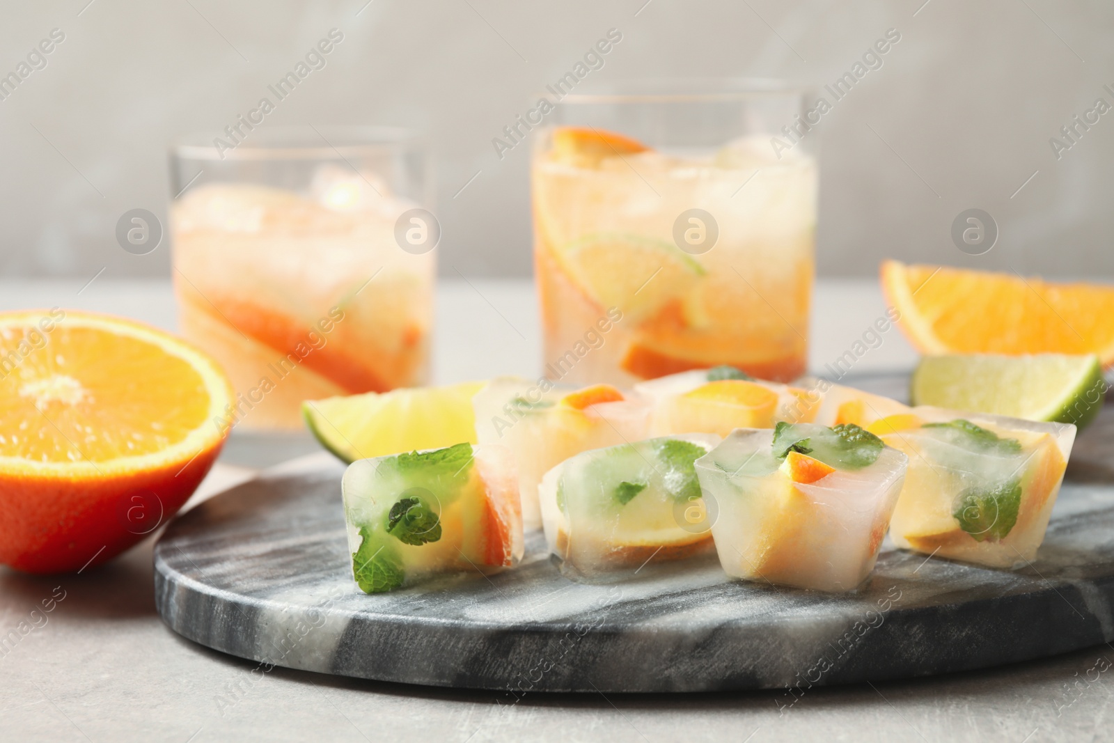Photo of Ice cubes with orange and mint on light grey table