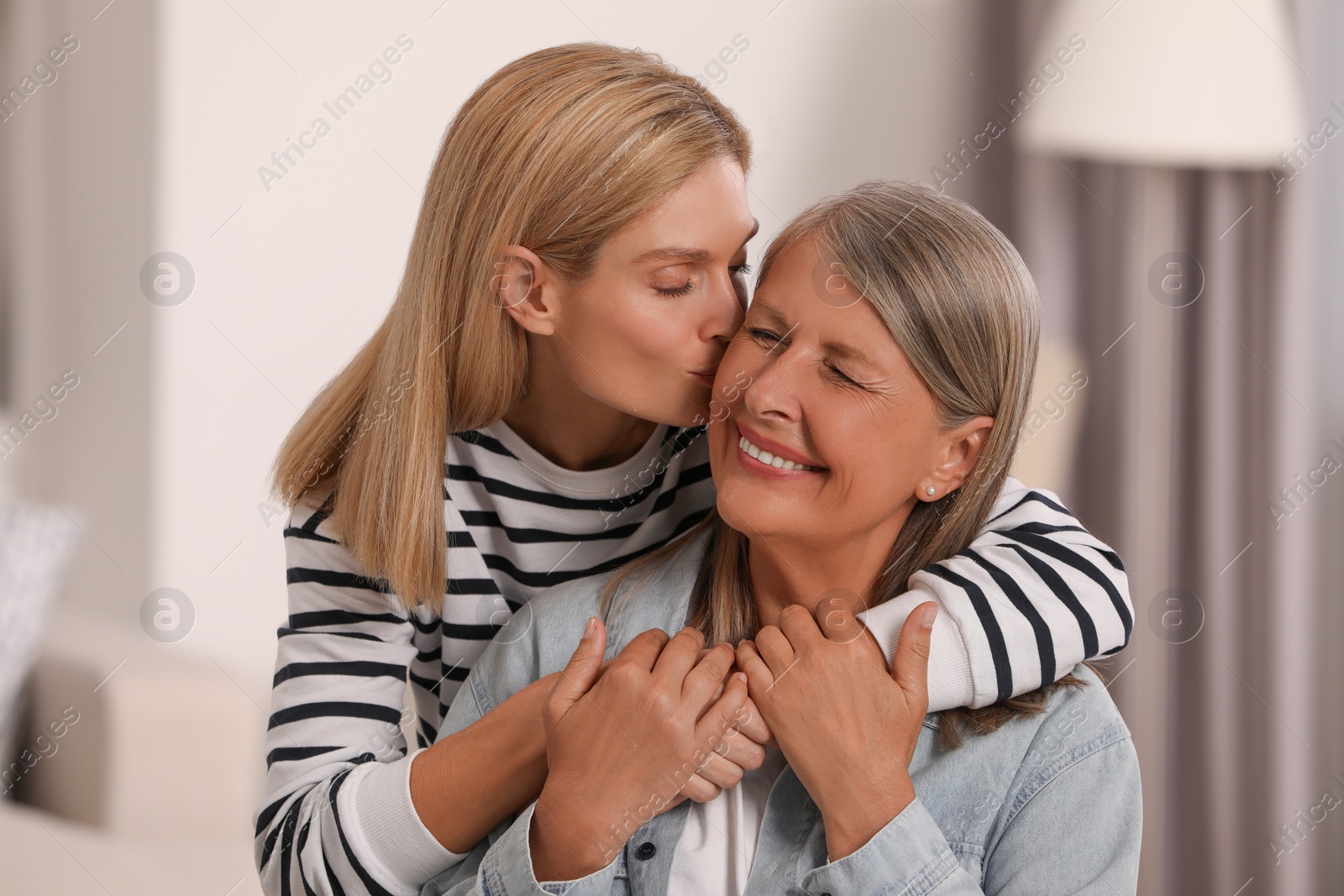 Photo of Daughter kissing her mature mother at home