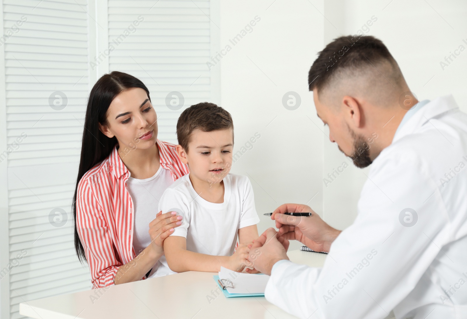 Photo of Little boy with mother visiting orthopedist at clinic