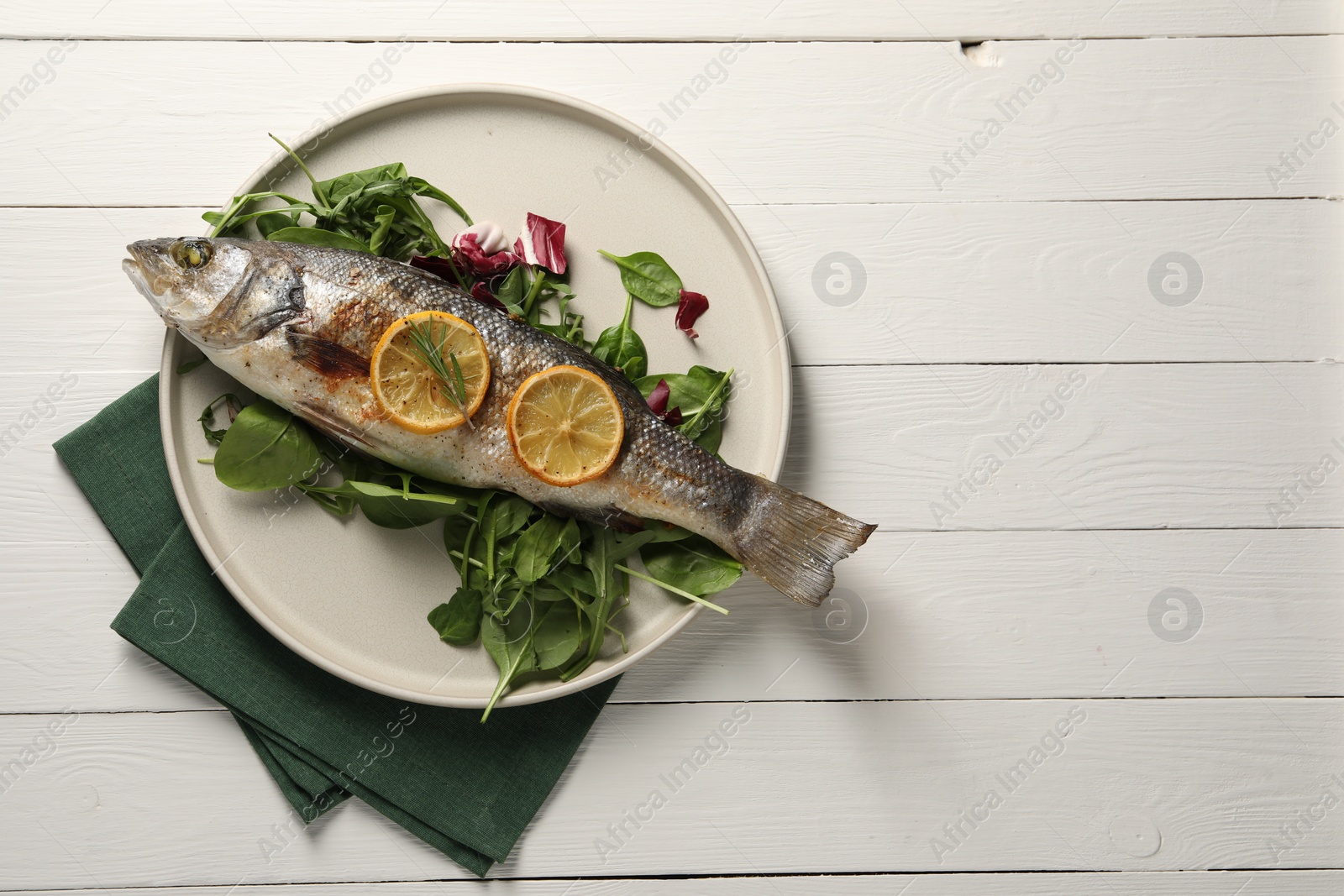 Photo of Baked fish with spinach and lemon on white wooden table, top view. Space for text