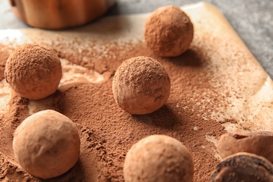 Photo of Sweet chocolate truffles powdered with cacao on parchment paper