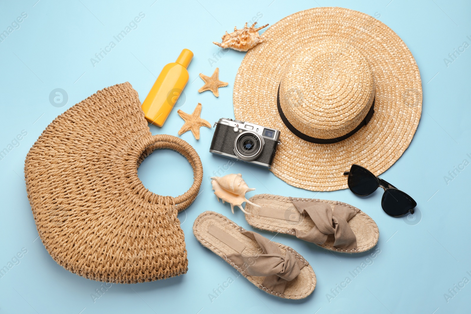 Photo of Stylish bag with beach accessories on turquoise background, flat lay