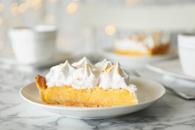 Photo of Plate with piece of delicious lemon meringue pie on white marble table