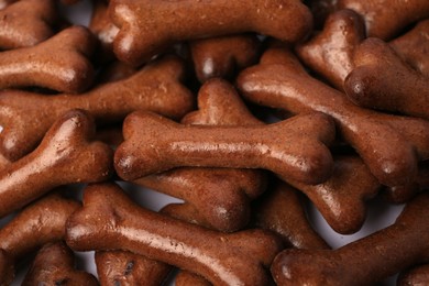 Many bone shaped dog cookies on white background, closeup