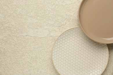 Beautiful ceramic plates on beige table, top view. Space for text