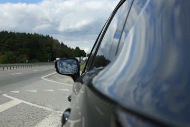 Photo of New black modern car outdoors, closeup of side rear view mirror
