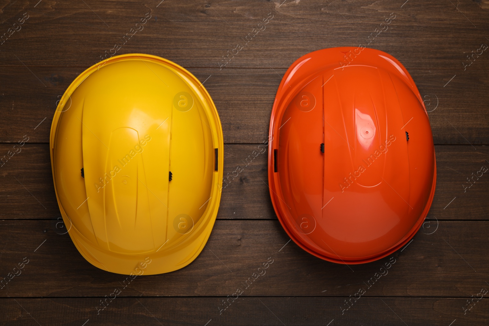 Photo of Hard hats on wooden table, flat lay. Safety equipment