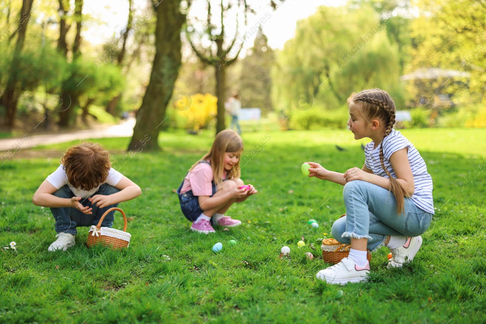 Photo of Easter celebration. Cute little children hunting eggs outdoors