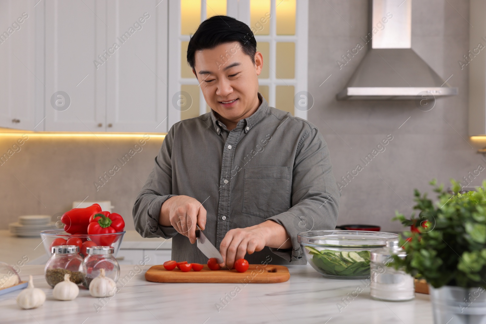 Photo of Cooking process. Man cutting fresh tomatoes at countertop in kitchen