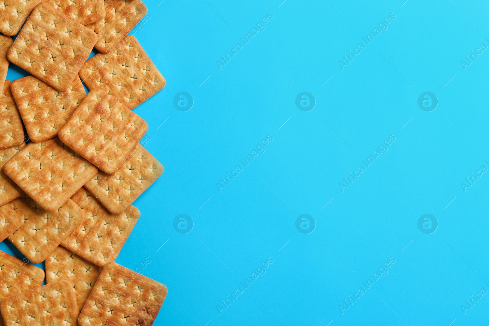 Photo of Delicious crackers on light blue background, flat lay. Space for text