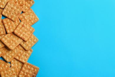 Photo of Delicious crackers on light blue background, flat lay. Space for text