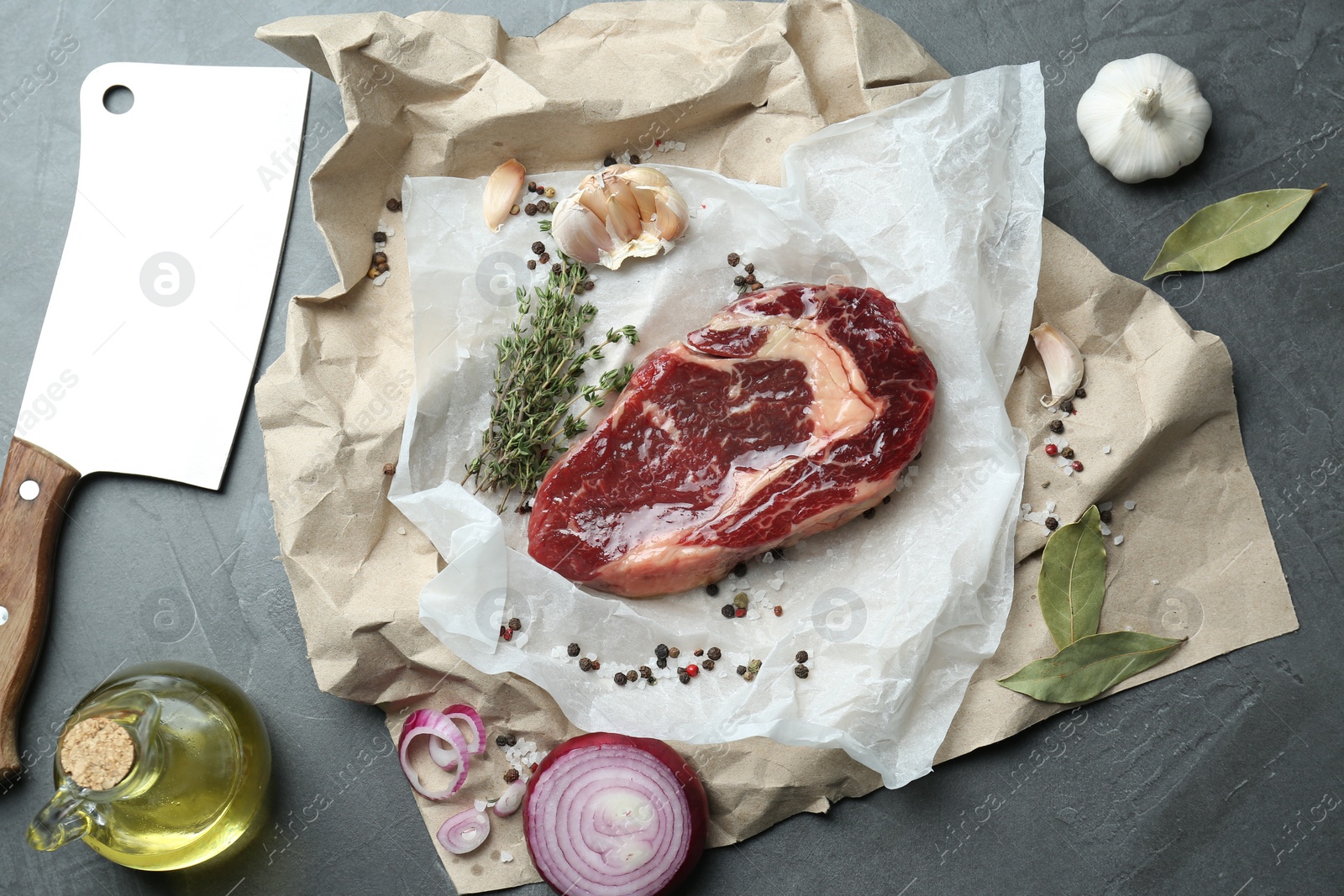 Photo of Piece of raw beef meat, spices and knife on grey table, flat lay