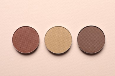 Different beautiful eye shadows on beige background, flat lay