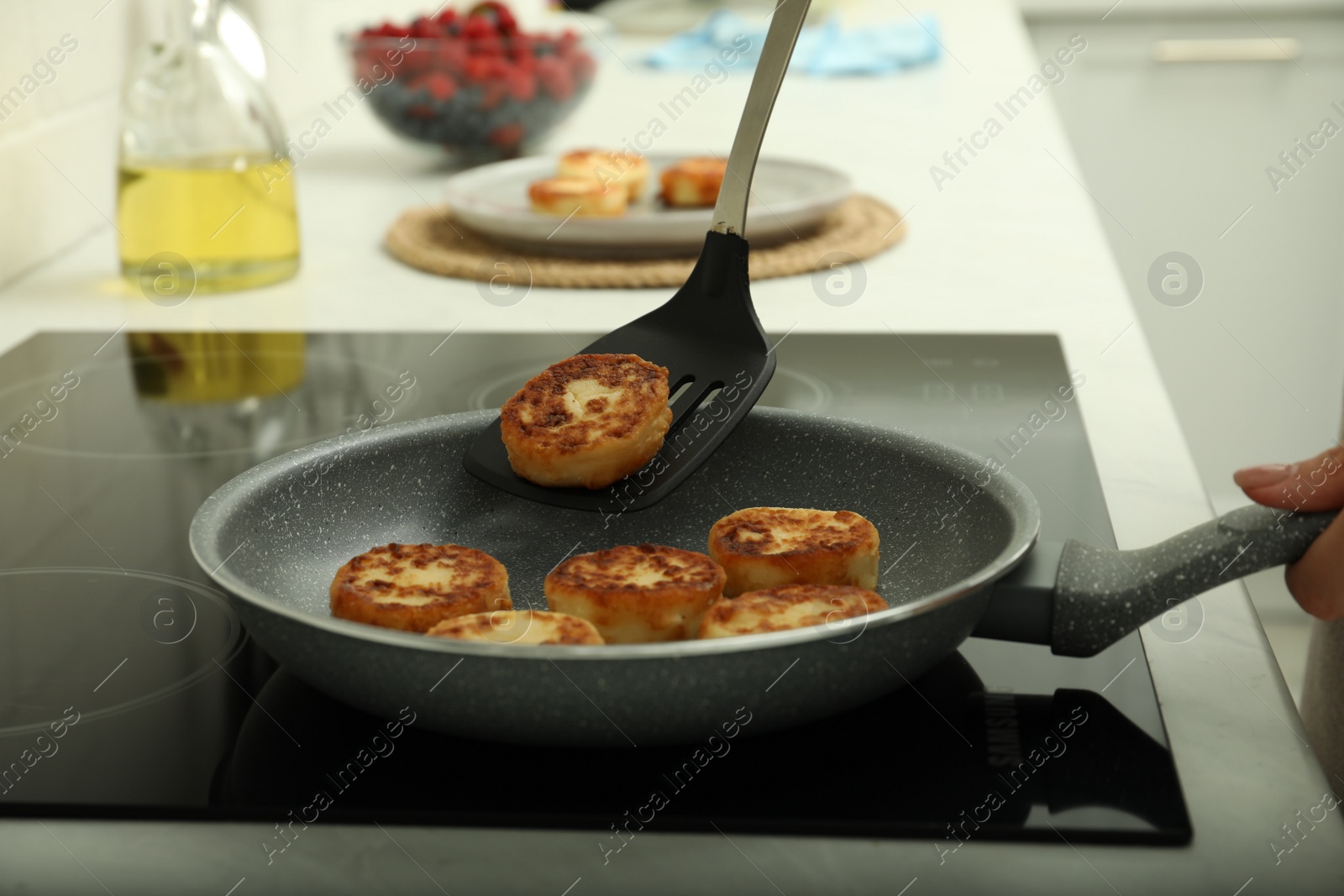 Photo of Woman frying delicious cottage cheese pancakes in kitchen, closeup