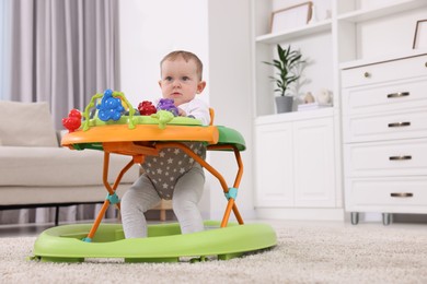Photo of Cute baby making first steps with toy walker at home, space for text