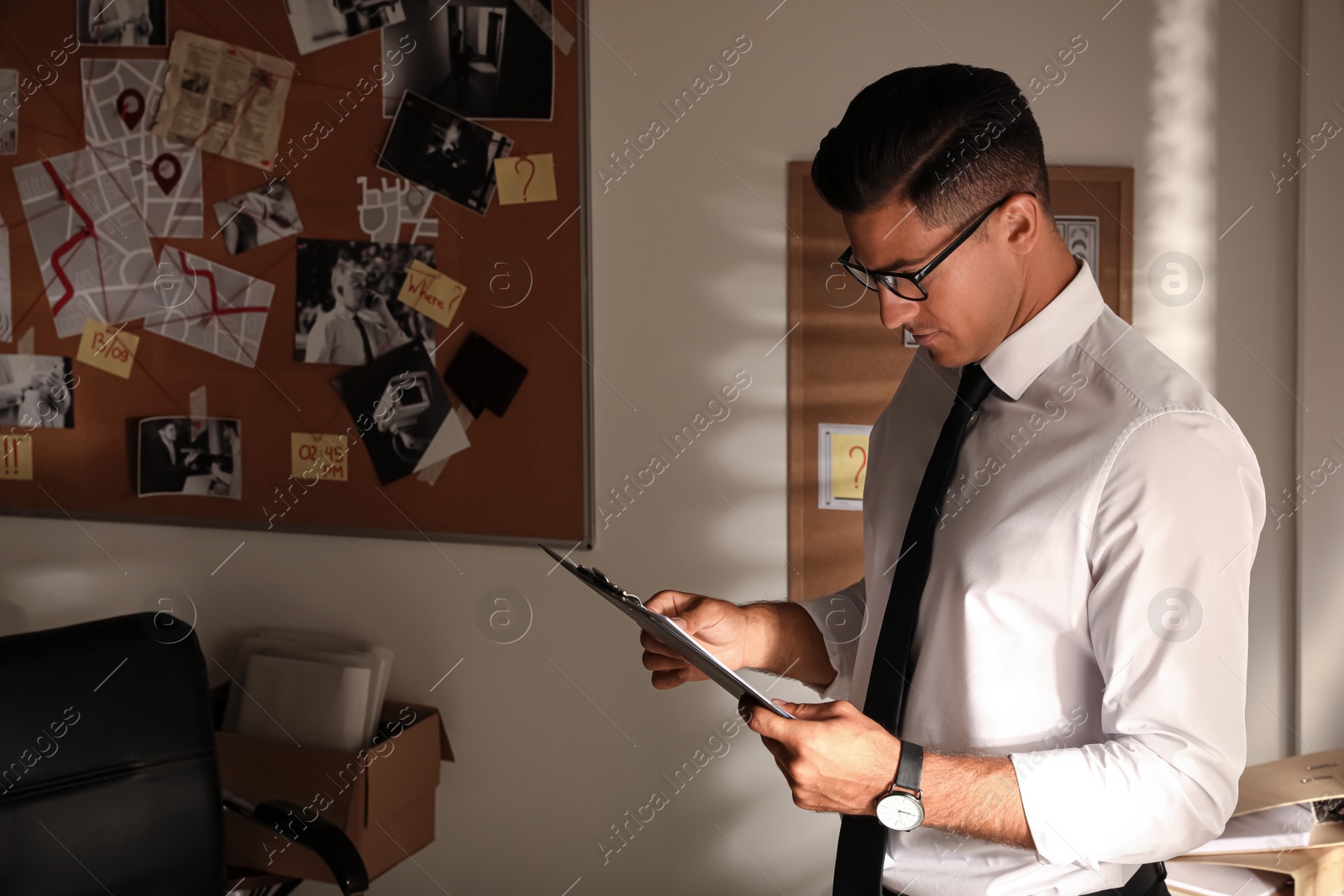 Photo of Detective with clipboard working in his office