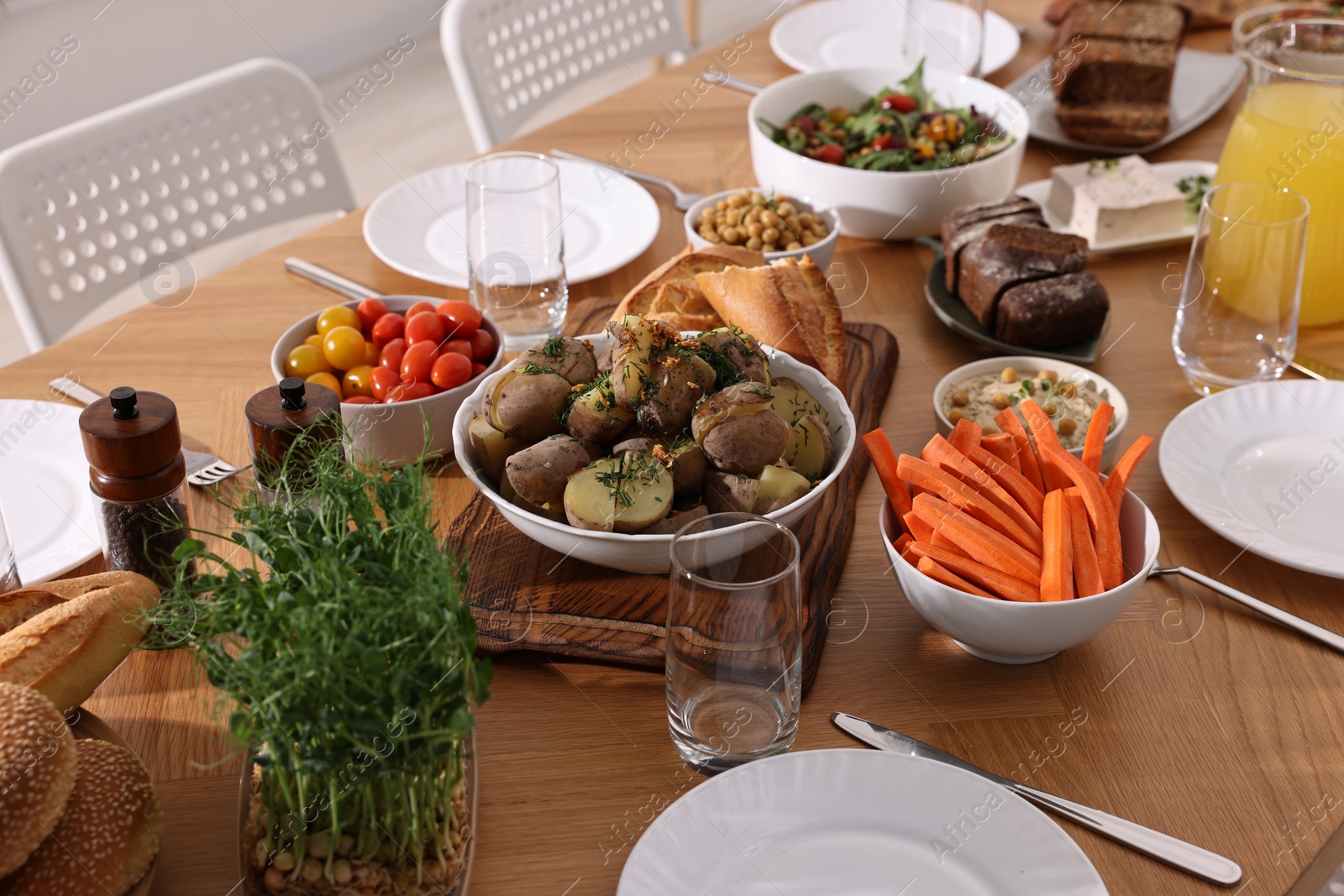 Photo of Healthy vegetarian food, glasses, cutlery and plates on wooden table indoors