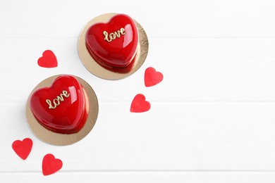 St. Valentine's Day. Delicious heart shaped cakes and confetti on white wooden table, flat lay. Space for text