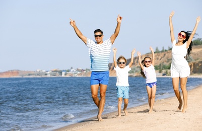 Happy family walking on sandy beach near sea. Summer holidays