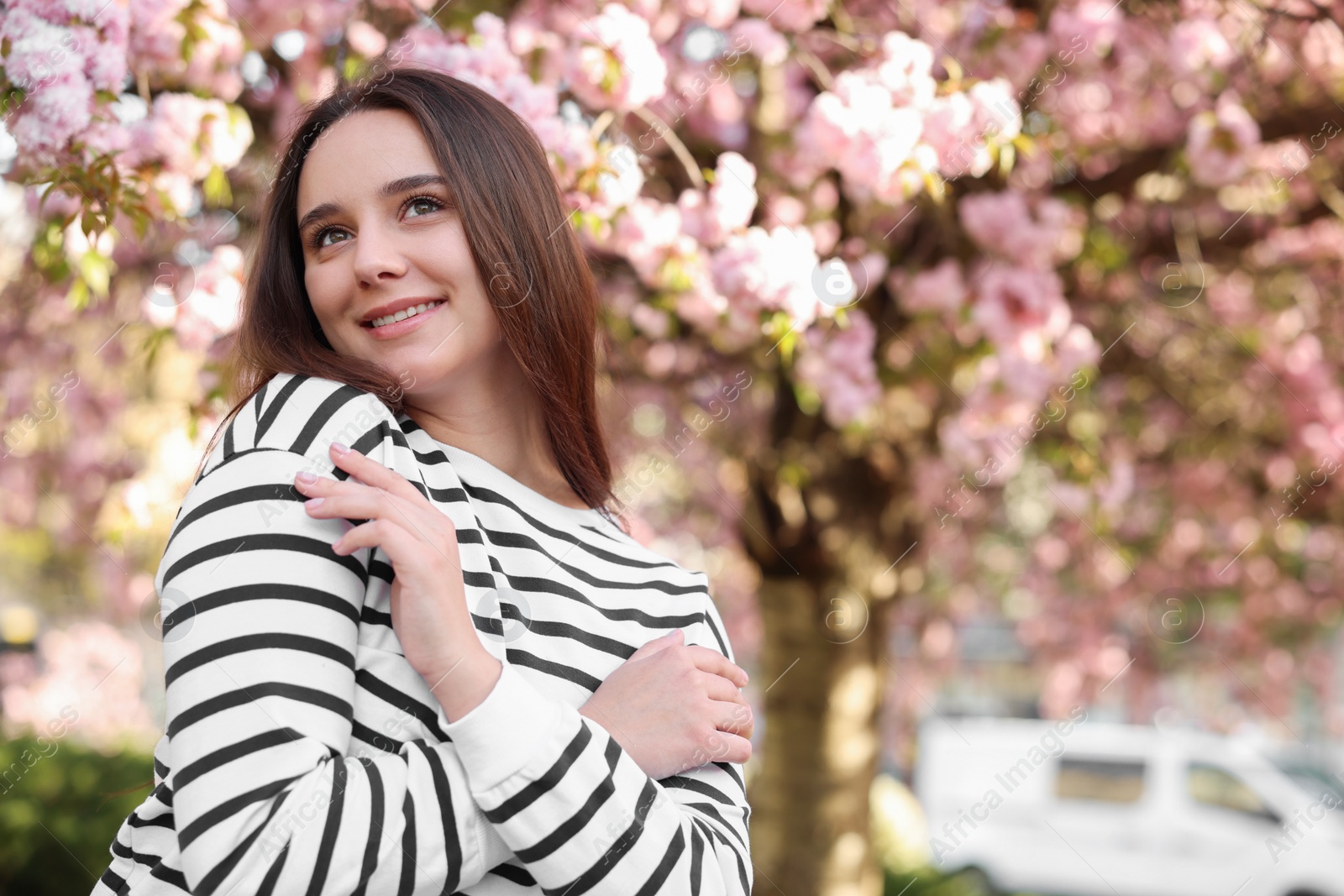 Photo of Beautiful woman near blossoming tree on spring day, space for text