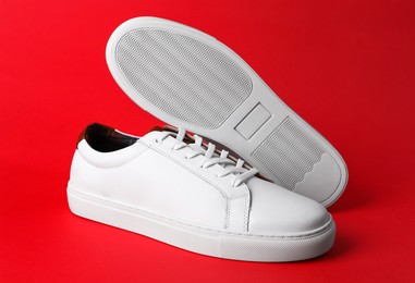 Photo of Pair of stylish sports shoes on red background