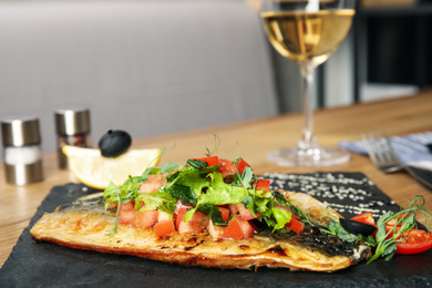 Photo of Delicious grilled fish with vegetables on slate plate