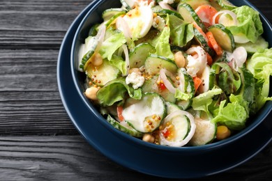 Photo of Bowl of delicious cucumber salad on black wooden table, closeup