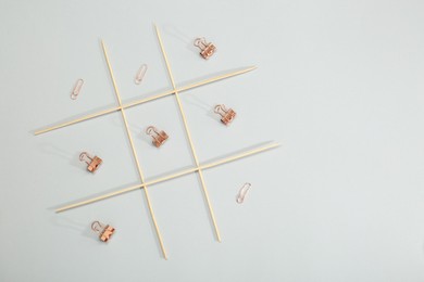 Photo of Tic tac toe game made with paper clips on light background, top view