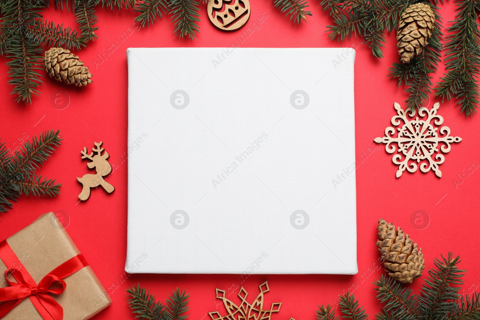 Photo of Flat lay composition with blank canvas and Christmas decor on red background. Mockup for design