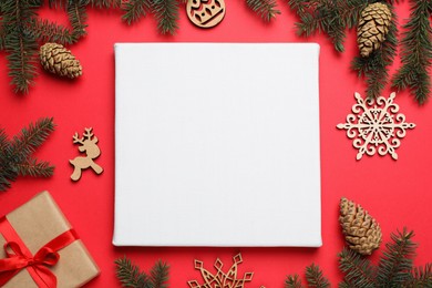 Photo of Flat lay composition with blank canvas and Christmas decor on red background. Mockup for design