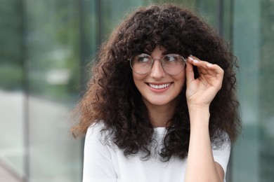 Portrait of beautiful woman in glasses on blurred background. Attractive lady smiling and posing for camera. Space for text