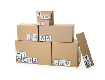 Photo of Stack of cardboard boxes with different packaging symbols on white background. Parcel delivery