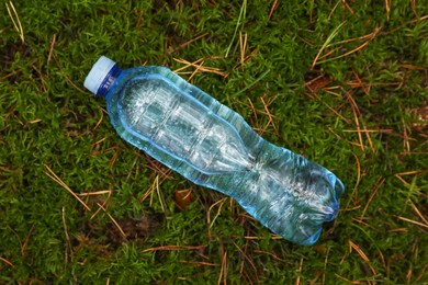 Plastic bottle of fresh water on green grass, top view