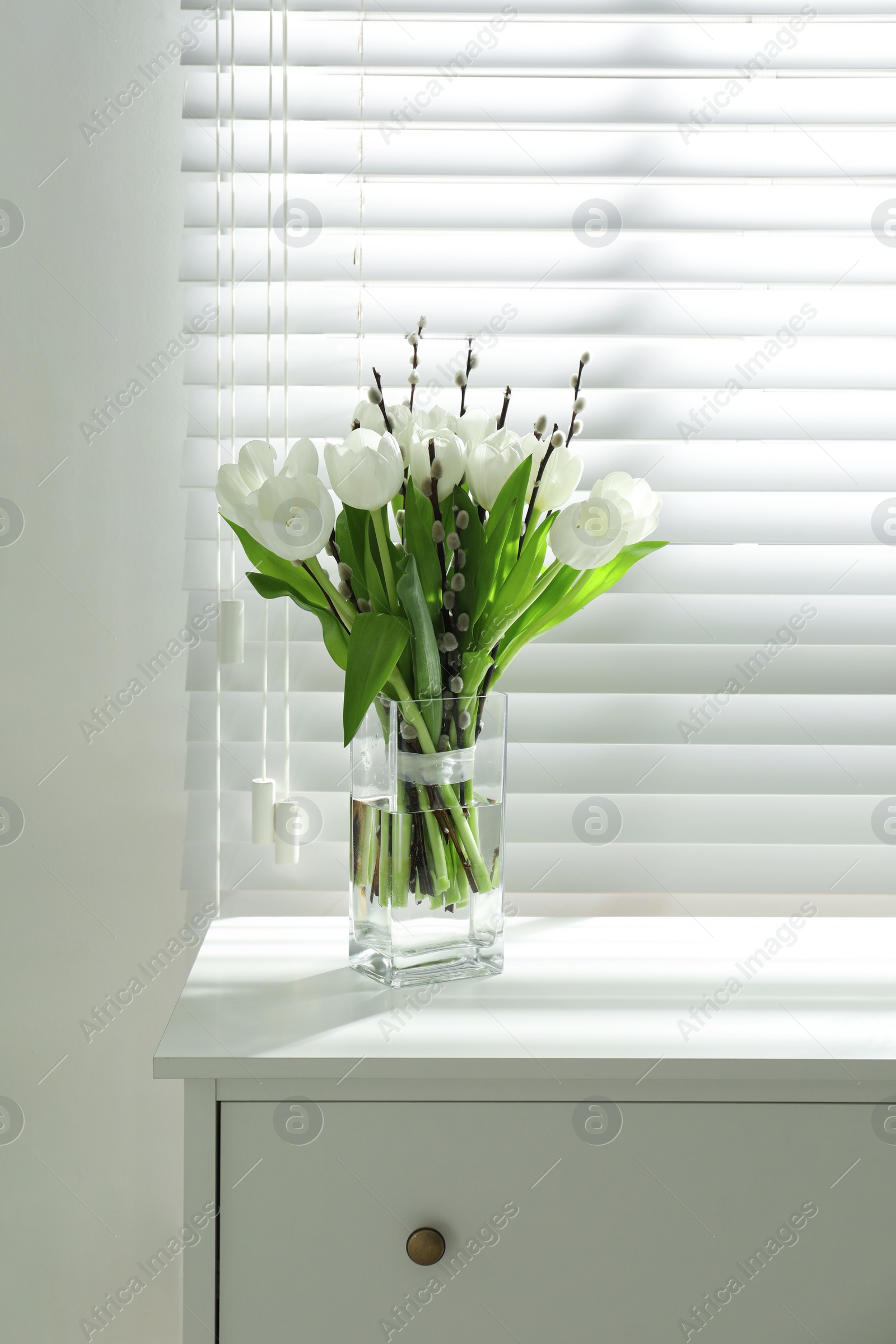 Photo of Beautiful bouquet of willow branches and tulips in vase near window