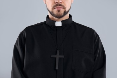 Priest wearing cassock with clerical collar on grey background, closeup