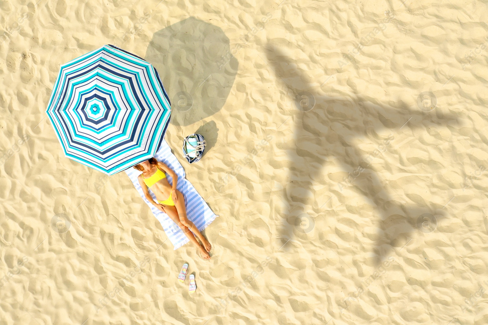 Image of Shadow of airplane and woman resting at sandy coast, aerial view. Summer vacation